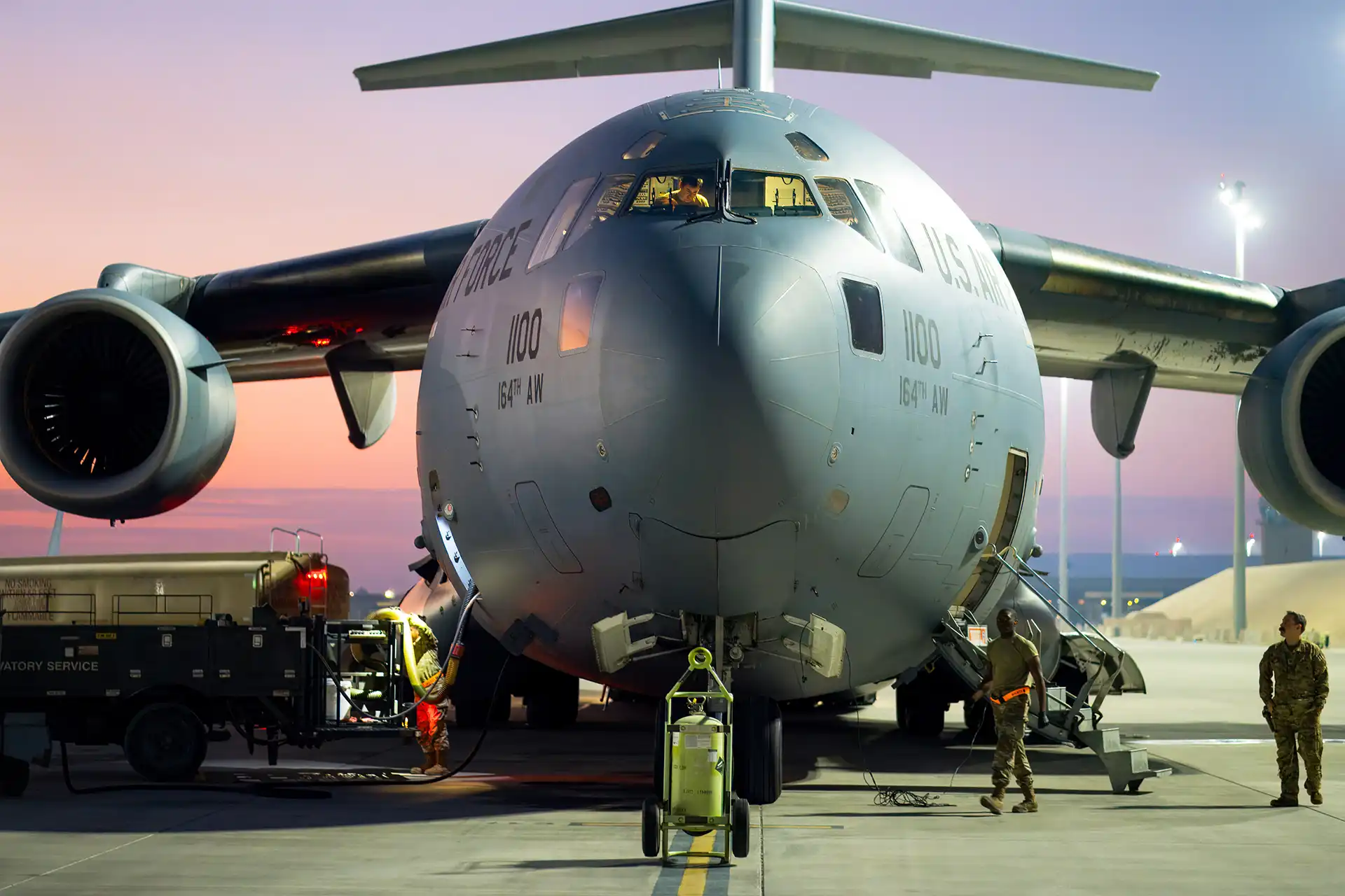 Ground crew preparing a C-17 Globemaster for a mission at dusk