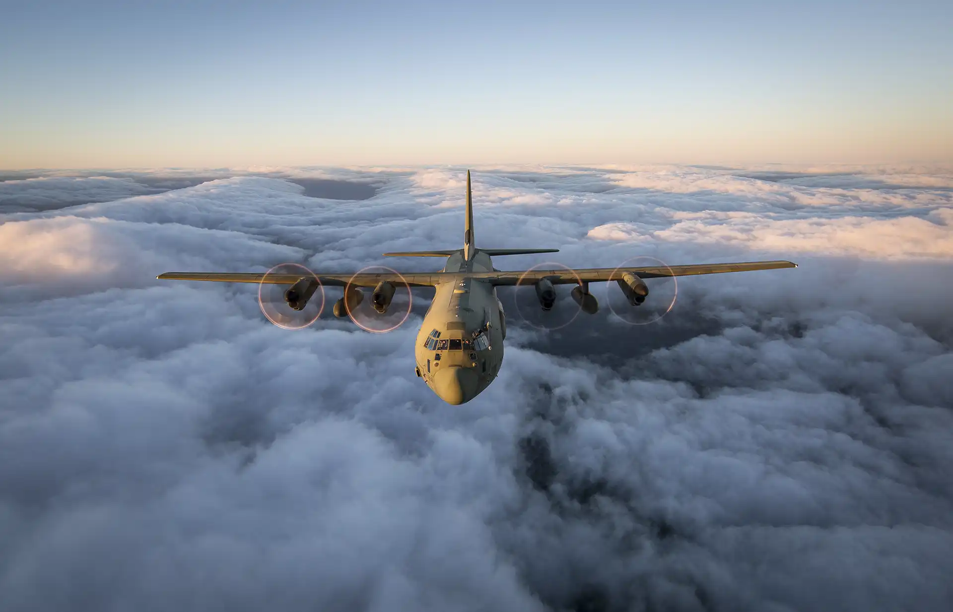 C-130 Hercules flying above the clouds at sunrise